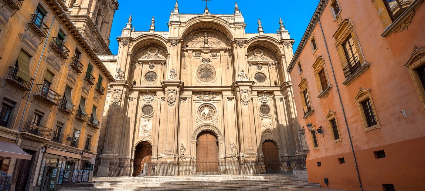 Fachada renacentista de la Catedral de Granada, con su imponente arquitectura y detalles ornamentales bajo la luz del sol.  