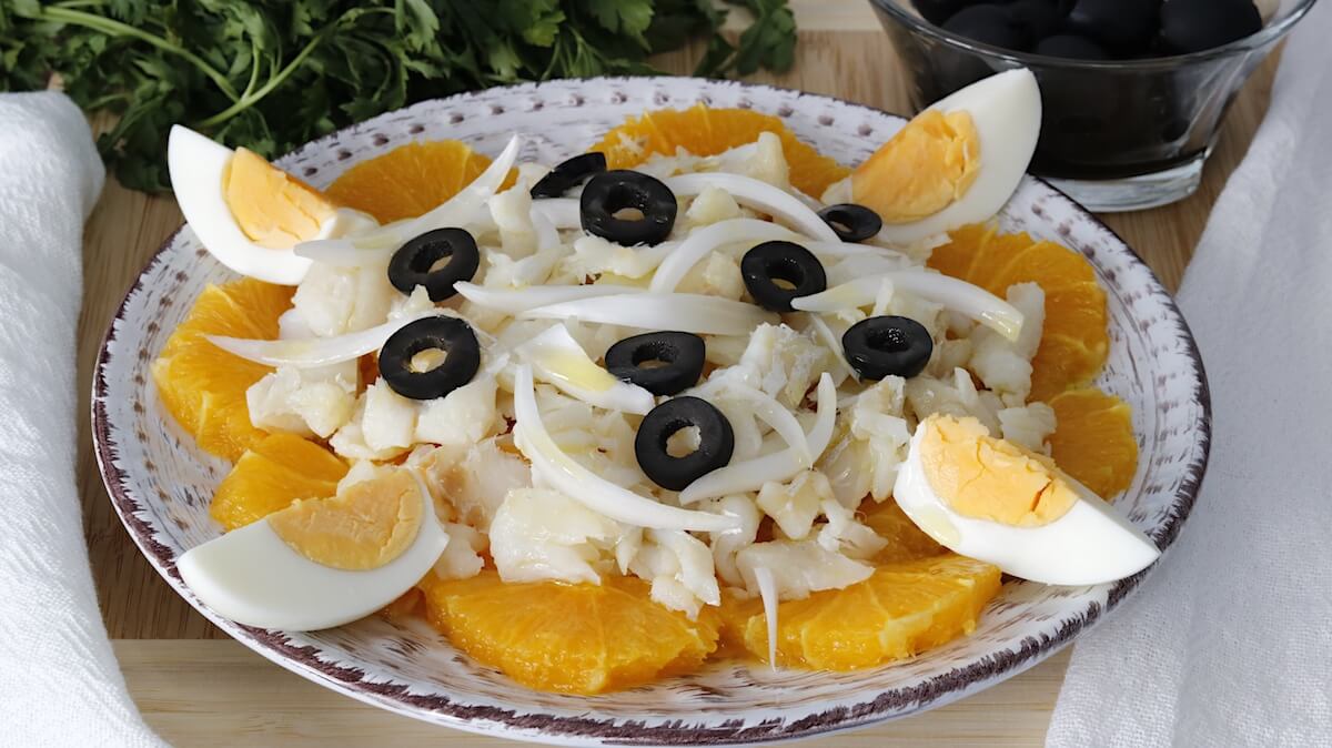 Plato tradicional de remojón granadino con bacalao desmigado, rodajas de naranja, cebolla, huevo cocido y aceitunas negras.  