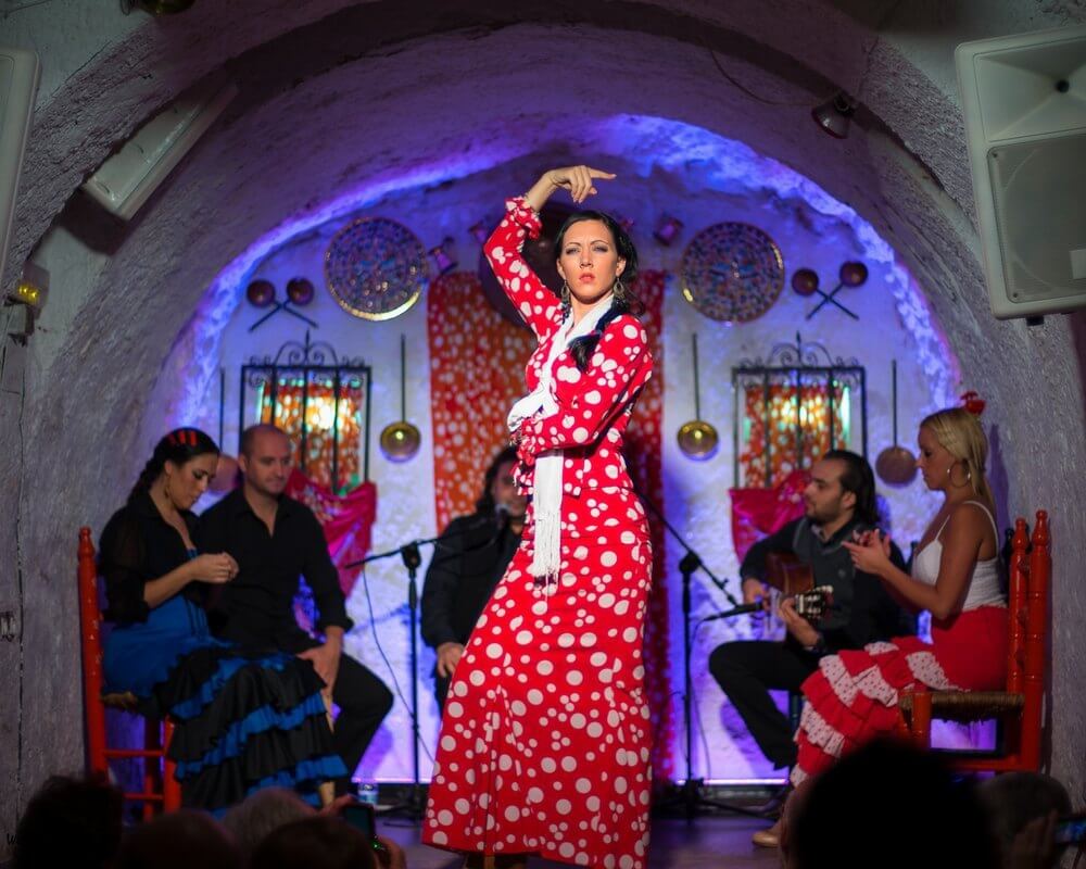 Espectáculo de flamenco en una cueva del Sacromonte, con una bailaora vestida de lunares interpretando un zapateado.