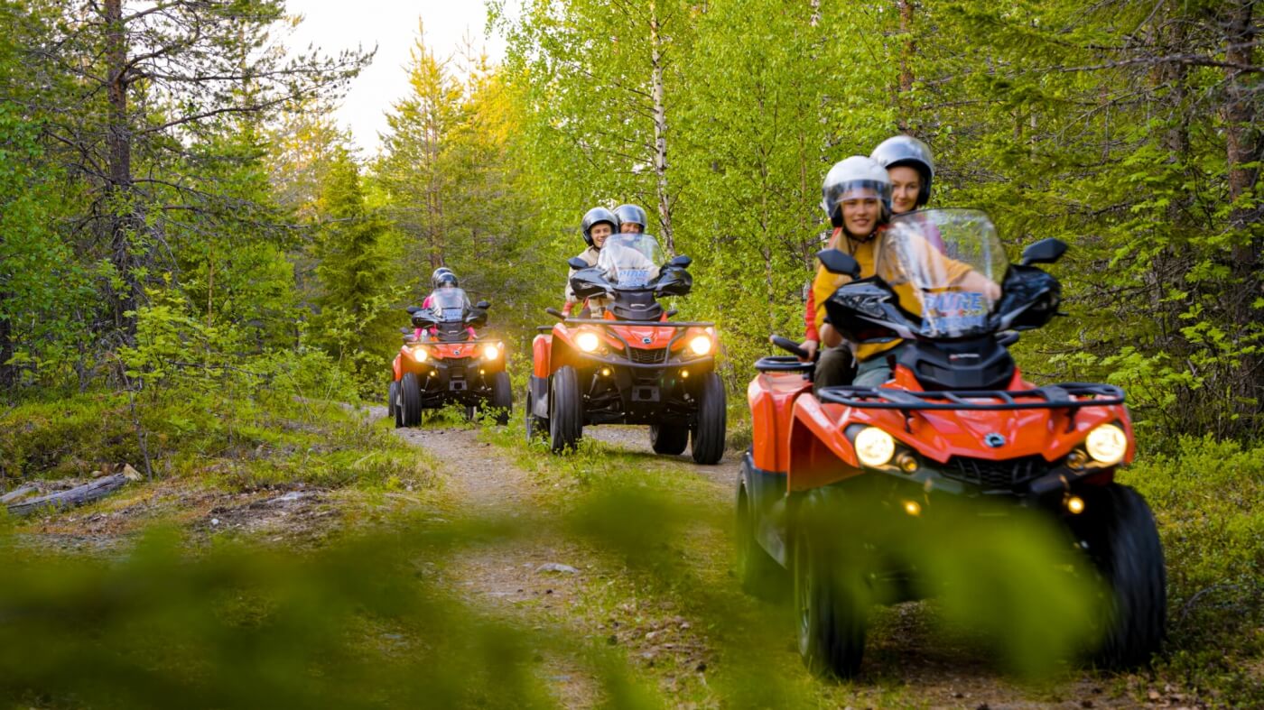 Grupo de viajeros recorriendo los bosques de Laponia en un safari en quad.